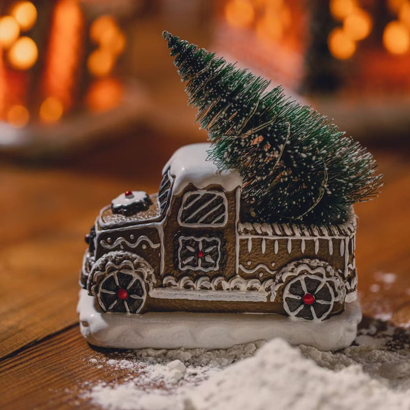 Hnedá vianočná svietiaca dekorácia v podobe autíčka s vianočným stromčekom.