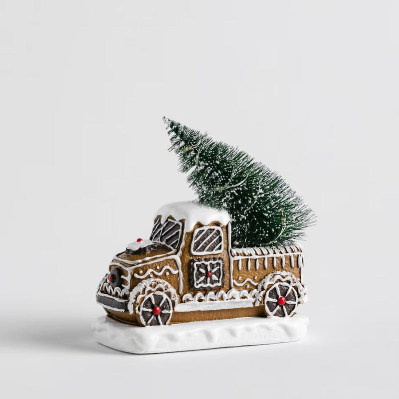 Hnedá vianočná svietiaca dekorácia v podobe autíčka s vianočným stromčekom.