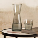 Sivá sklenená karafa s pohárom. 