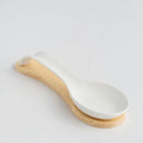 Biela porcelánová podložka na lyžičku s drevenou podložkou.