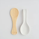 Biela porcelánová podložka na lyžičku s drevenou podložkou.