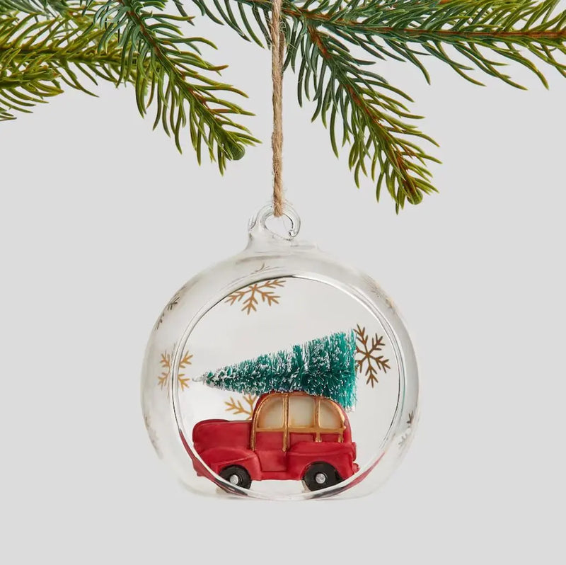 Červená vianočná ozdoba v podobe autíčka s vianočným stromčekom.