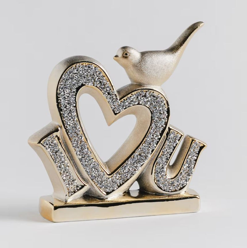 Zlatá dekorácia so srdiečkom a vtáčikom. Zobrazuje nápis I LOVE YOU.