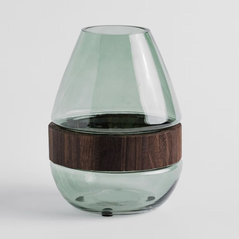 Zelená sklenená váza s dreveným doplnkom.