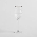 Transparentný pohár na likér so strieborným lemom.