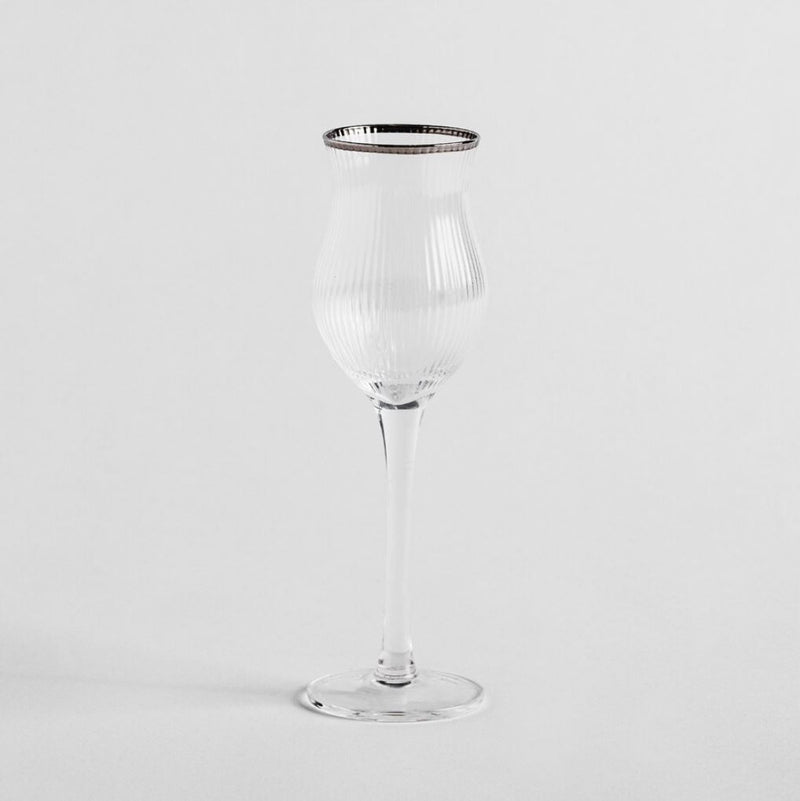 Transparentný pohár na likér so strieborným lemom.