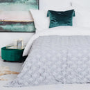 Sivý polyesterový prehoz na posteľ. 