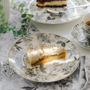 Sivý porcelánový plytký tanier s motívom sivého kvetu a zlatým okrajom. 